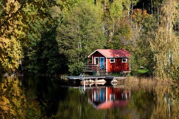Typical Swedish red little cottage at a lake
