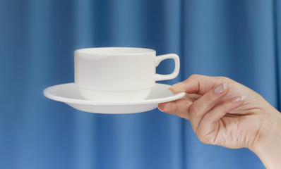 White cup in his hands on blue background