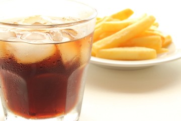 Glass of cola and fried potatoes on plate
