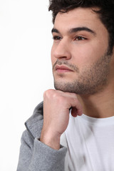 Fototapeta premium Pensive man stood touching chin with fist