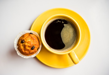 Coffee in an yellow cup and a muffin