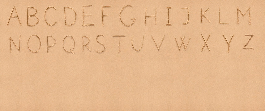 Handwriting English alphabet on flat sand with empty space appro