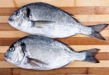 two fresh sea bream on a cutting board