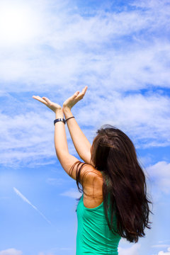 A young woman is holding her hands as a v in the sky