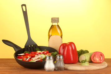 frying pan with vegetables on yellow background
