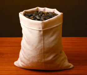 Cloth bag of sunflower seeds on wooden table on brown