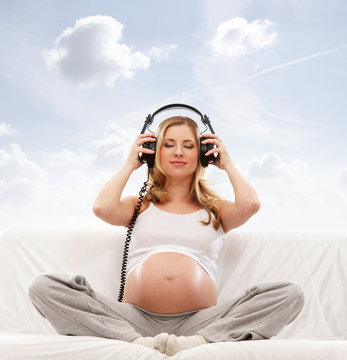 A young blond pregnant woman listening to the music