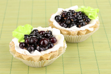sweet cakes with berries on green bamboo mat