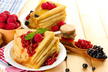 Delicious pancakes with berries, jam and honey on wooden table