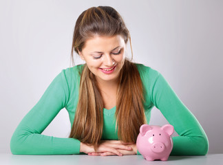 Young beautiful woman with piggy bank (money box)