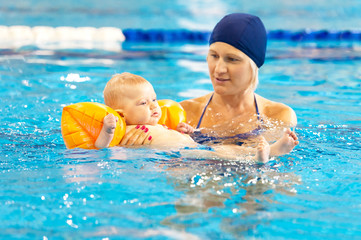 mother teach baby swimming in pool