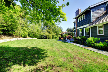 Fototapeta na wymiar Blue large house with backyard and green landscape.