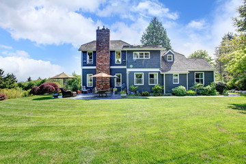 Fototapeta na wymiar Duży niebieski dom z trawą i komina.