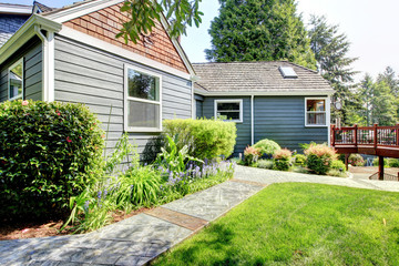 Grey house with deck and green landscape.