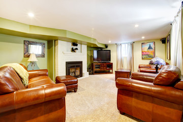 Tv room with green walls, leather sofas and fireplace.
