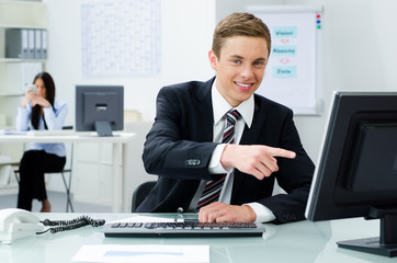 junger geschäftsmann zeigt auf seinen bildschirm