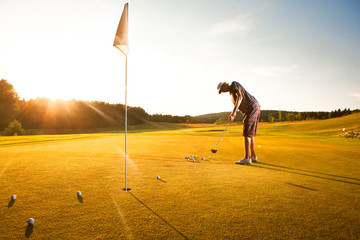 Male golf player practicing a par during sunset