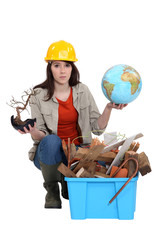Woman with globe in hand kneeling by waste materials