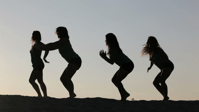 Carefree women dancing in the sunset on the beach