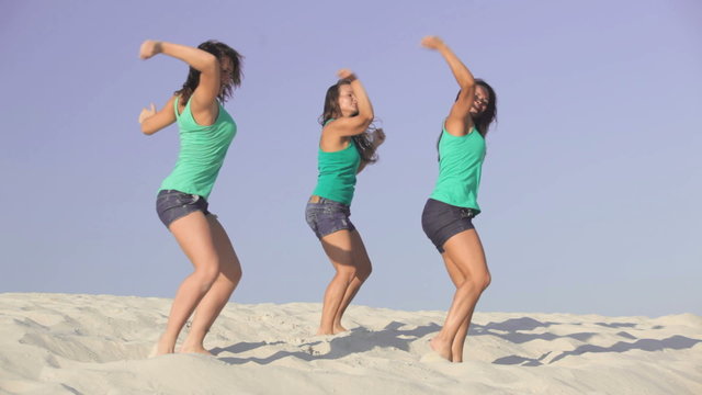 Team of pretty energetic girls dancing on the sand together