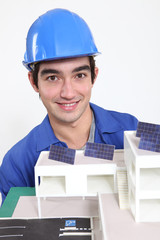 Tradesman posing with an eco-friendly building model