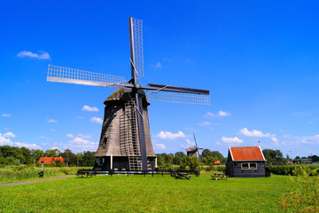 Fototapeta na wymiar Tradycyjny holenderski wiatrak pod błękitnym niebem w pobliżu Almaar