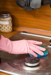 hand of the person in a rubber glove cleans a cooker