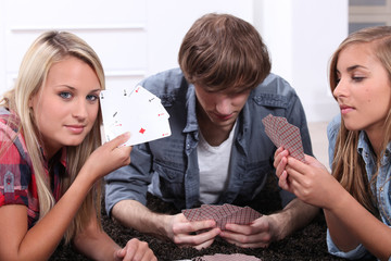 Three teenagers playing cards.