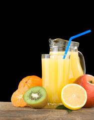 fresh tropical fruits and juice in glass isolated on black