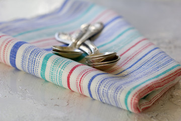 Set of silver teaspoons on the colourful kitchen towel