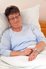 Seniorin mit Ruf Hile Notfall Telefon im Bett