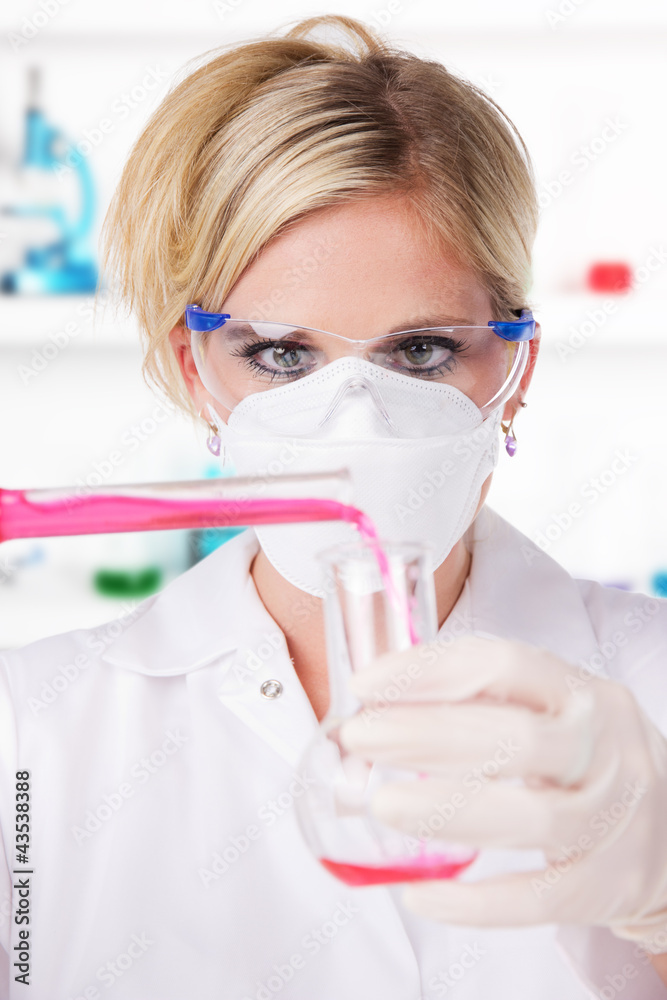 Wall mural Young attractive laboratory assistant pouring chemical liquid