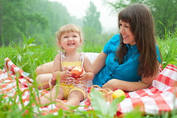 mother and daughter have picnic eating apples outdoor