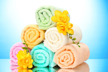 Obraz na płótnie Canvas kolorowe ręczniki i kwiaty na niebieskim tle