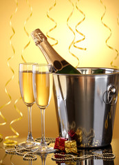 Champagne bottle in bucket with ice and glasses of champagne,