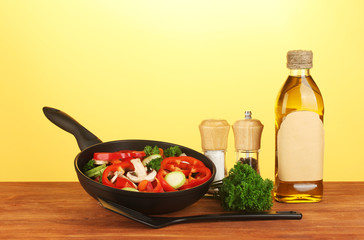 frying pan with vegetables on yellow background