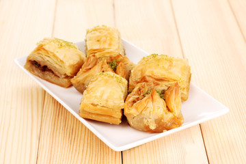 Sweet baklava on plate on wooden background