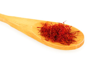 stigmas of saffron in wooden spoon on white background close-up