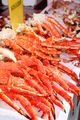 Fresh red king-crab legs in ice at seafood market;