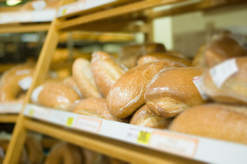 Variety of fresh wheat bread on shelves in supermarket