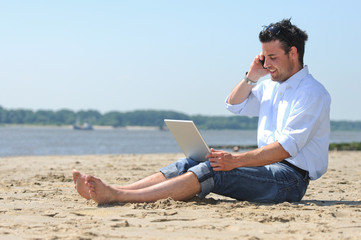 Geschäftsmann am Strand mit Laptop und Smartphone