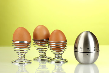 egg timer and egg in metal stand on green background