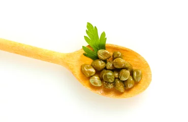 Foto op Plexiglas green capers in wooden spoon on white background close-up © Africa Studio