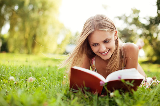 Young Woman Reading Book At Park Lying Down On Grass