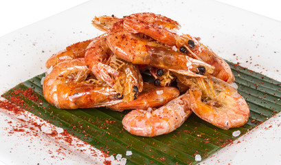 fried black tiger prawns with herbs and spices on banana leaf