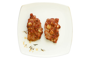 two pieces of pork steak on a white plate isolated