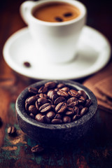 Espresso coffee beans; cup of coffee in background
