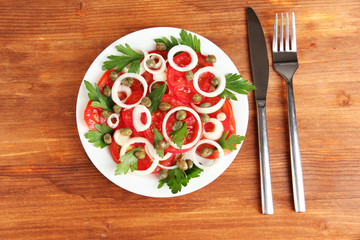 Salad with capers in the plate on wooden background