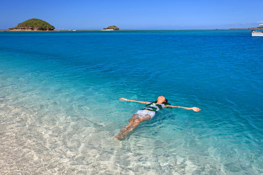 南国沖縄の綺麗なビーチで寛ぐ女性