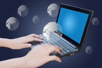 Hand pushing laptop keyboard with globe.